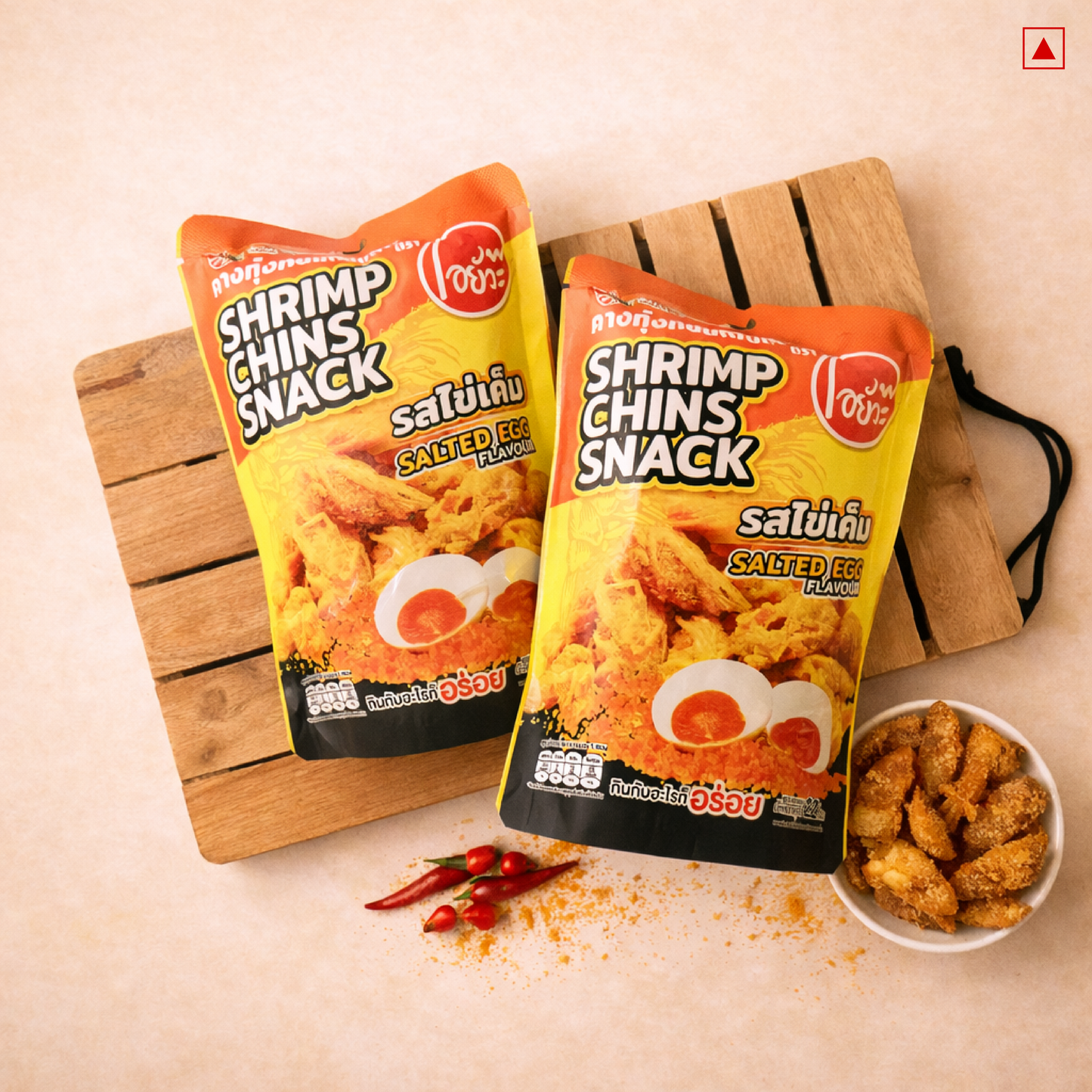 Two packages of Shrimp Chins Snack with a bowl of snacks on a wooden board.