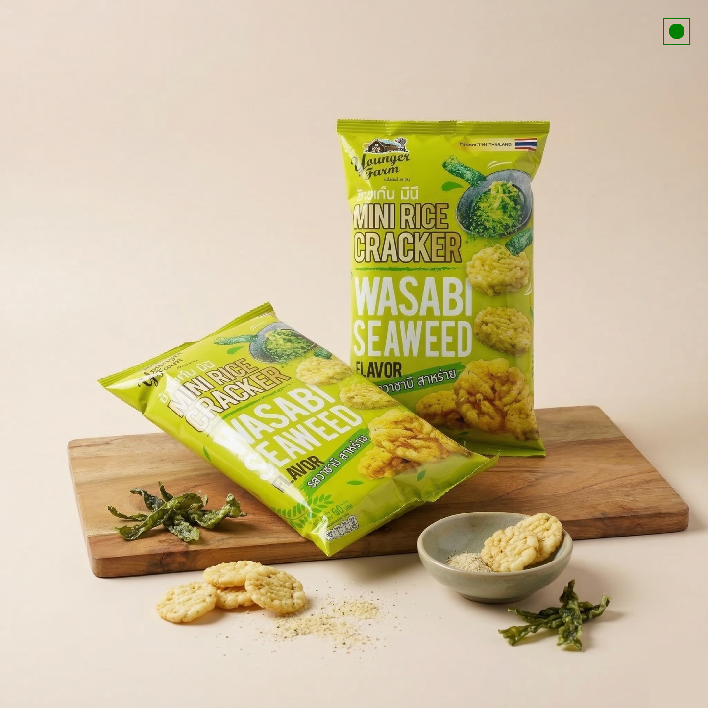 Two packages of Wasabi Seaweed Mini Rice Crackers on a wooden board with a small bowl of crackers and wasabi leaves.