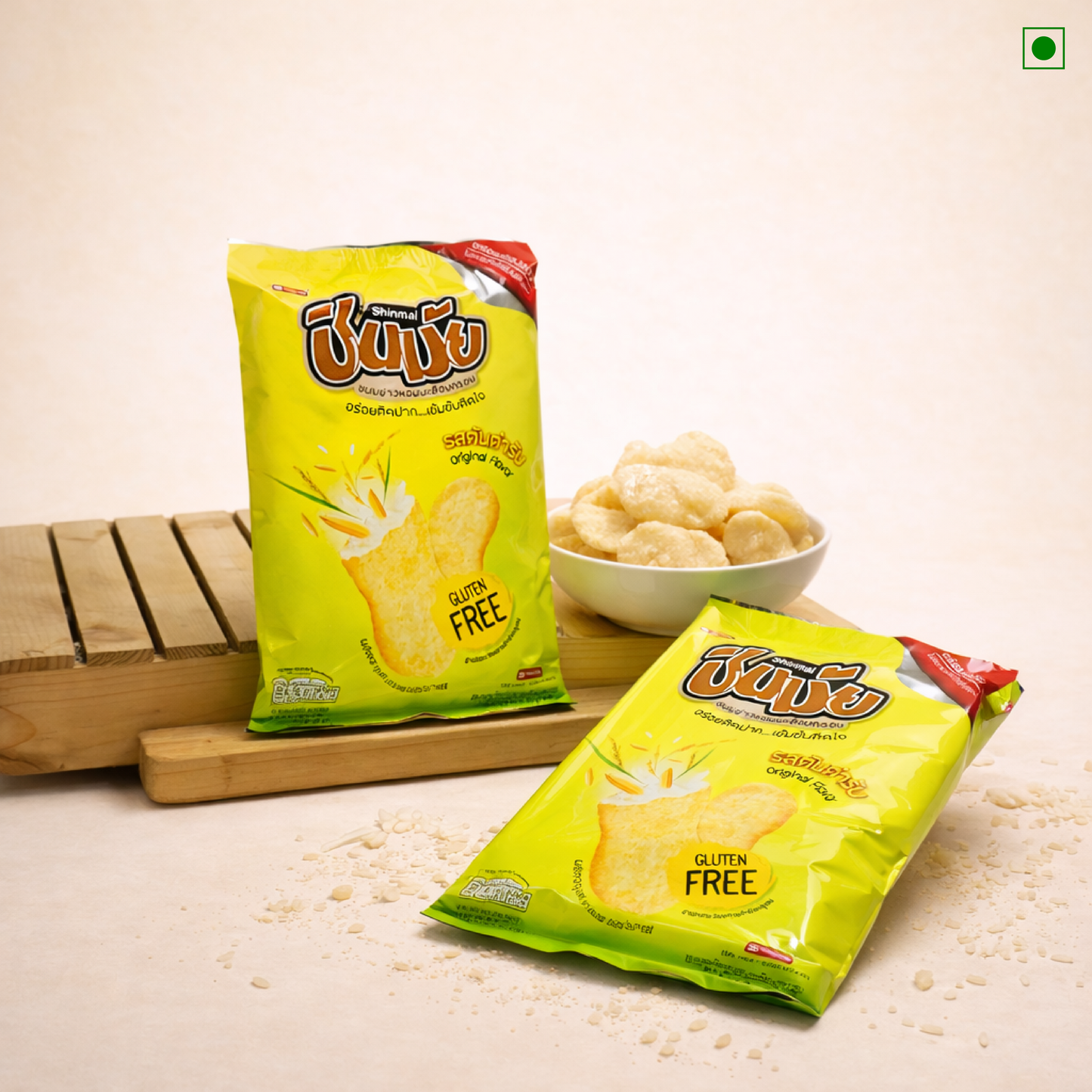 Two packs of gluten-free snacks on a wooden surface with a bowl of snacks.