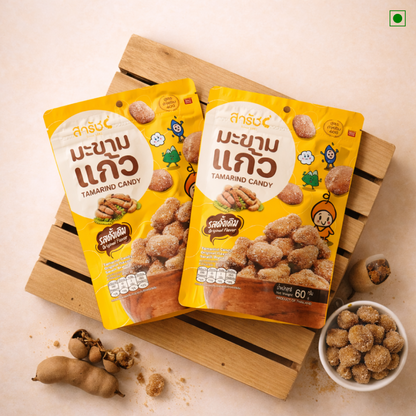 Tamarind candy with tamarind pods and a bowl of candy on a wooden board
