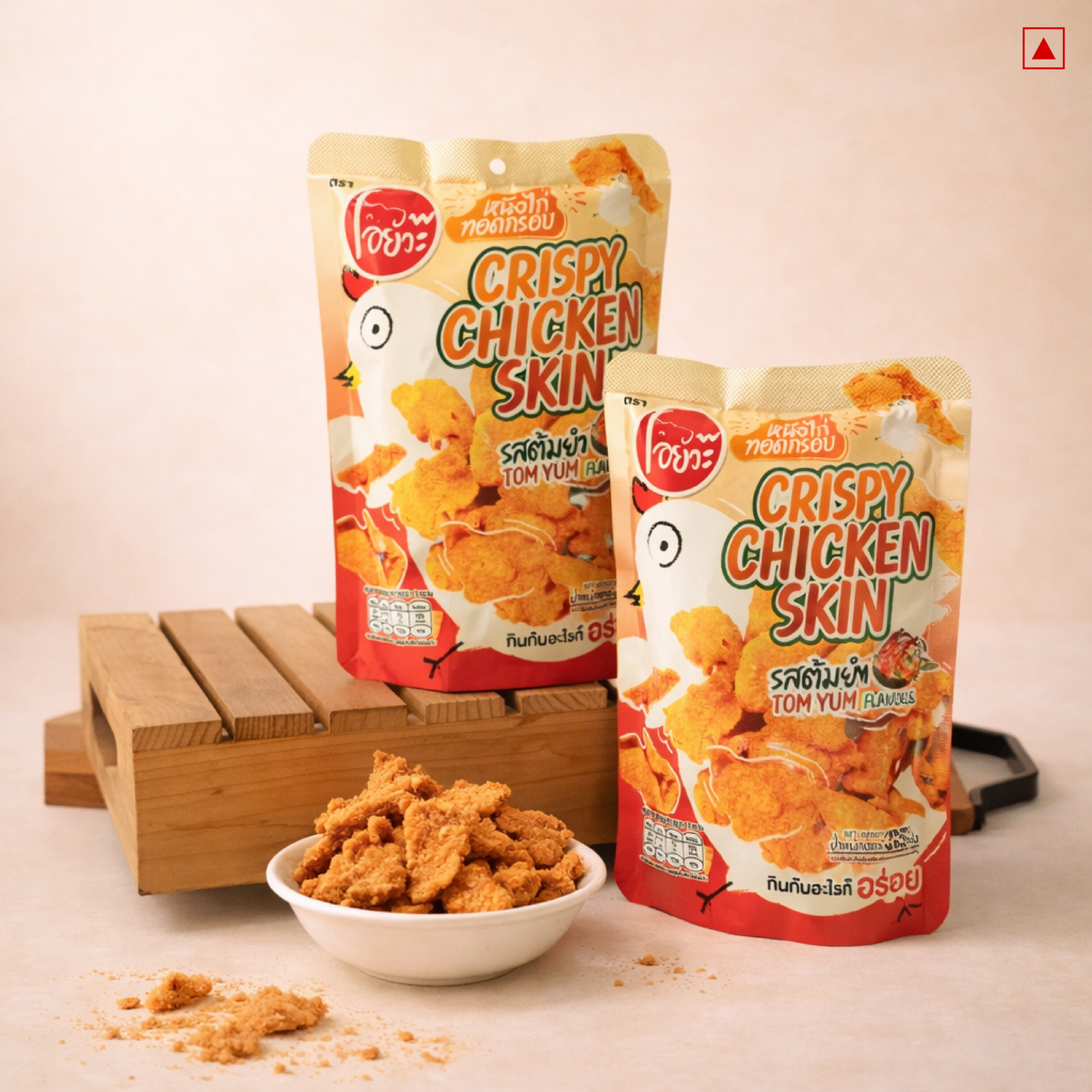 Two packages of crispy chicken skin snacks with a bowl of snacks on a wooden stand.