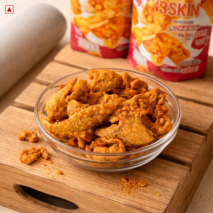 Glass bowl of crispy fried chicken skin on a wooden surface with the packaging in the background.