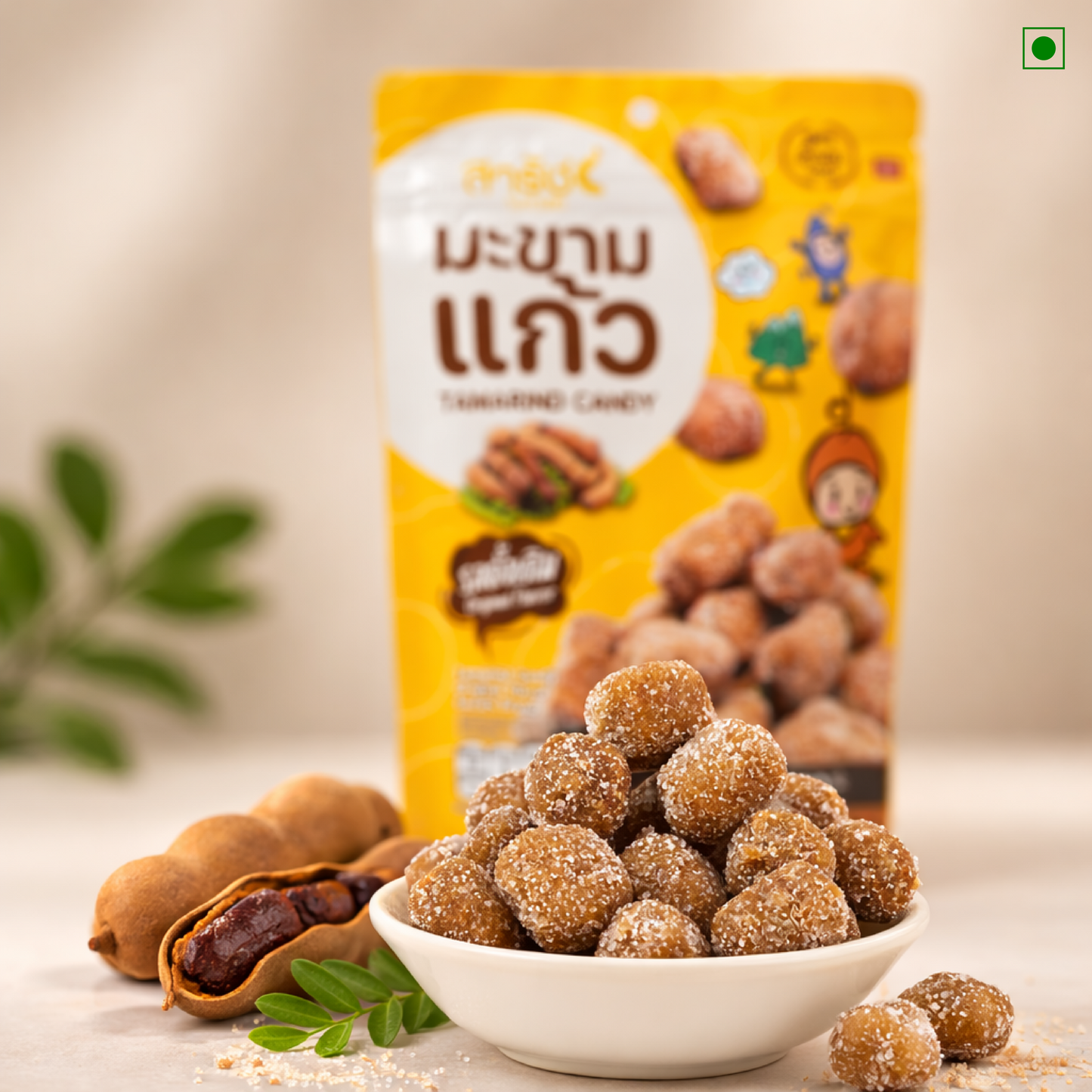 Bowl of tamarind candies with a package in the background on a light surface.