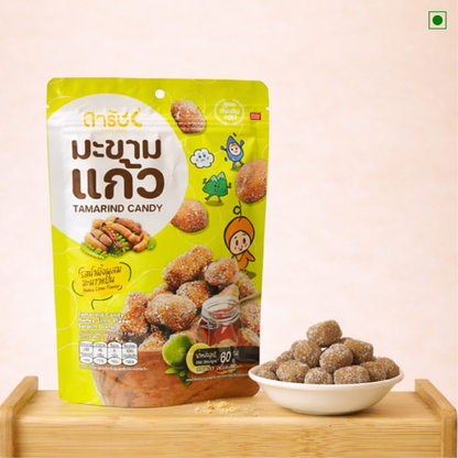 Packaging of tamarind candy with a bowl of candy on a wooden stand against a beige background