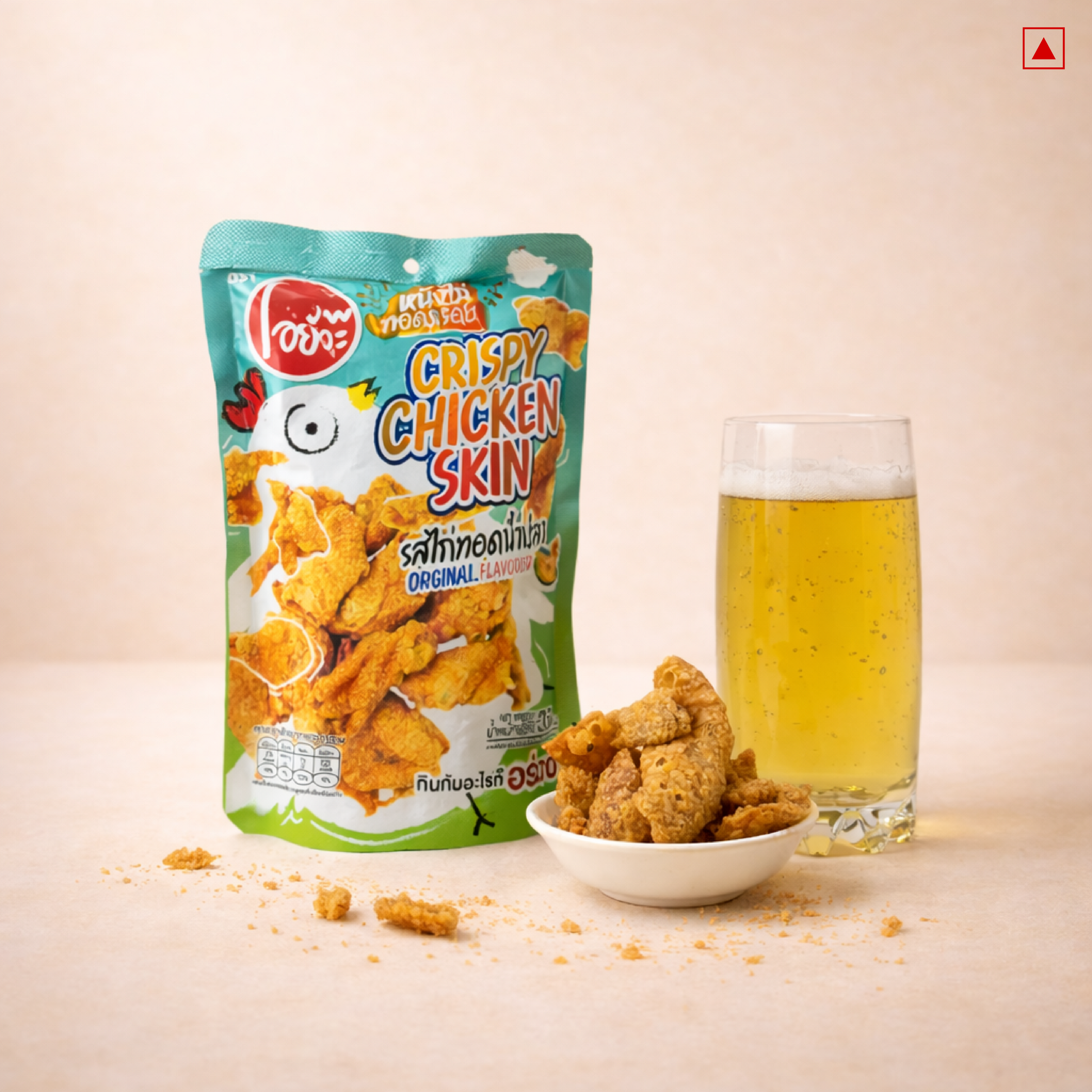 Packaged crispy chicken skin with a glass of beer on a beige background