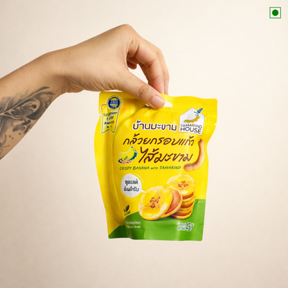 Hand holding a yellow snack package with branding on a beige background