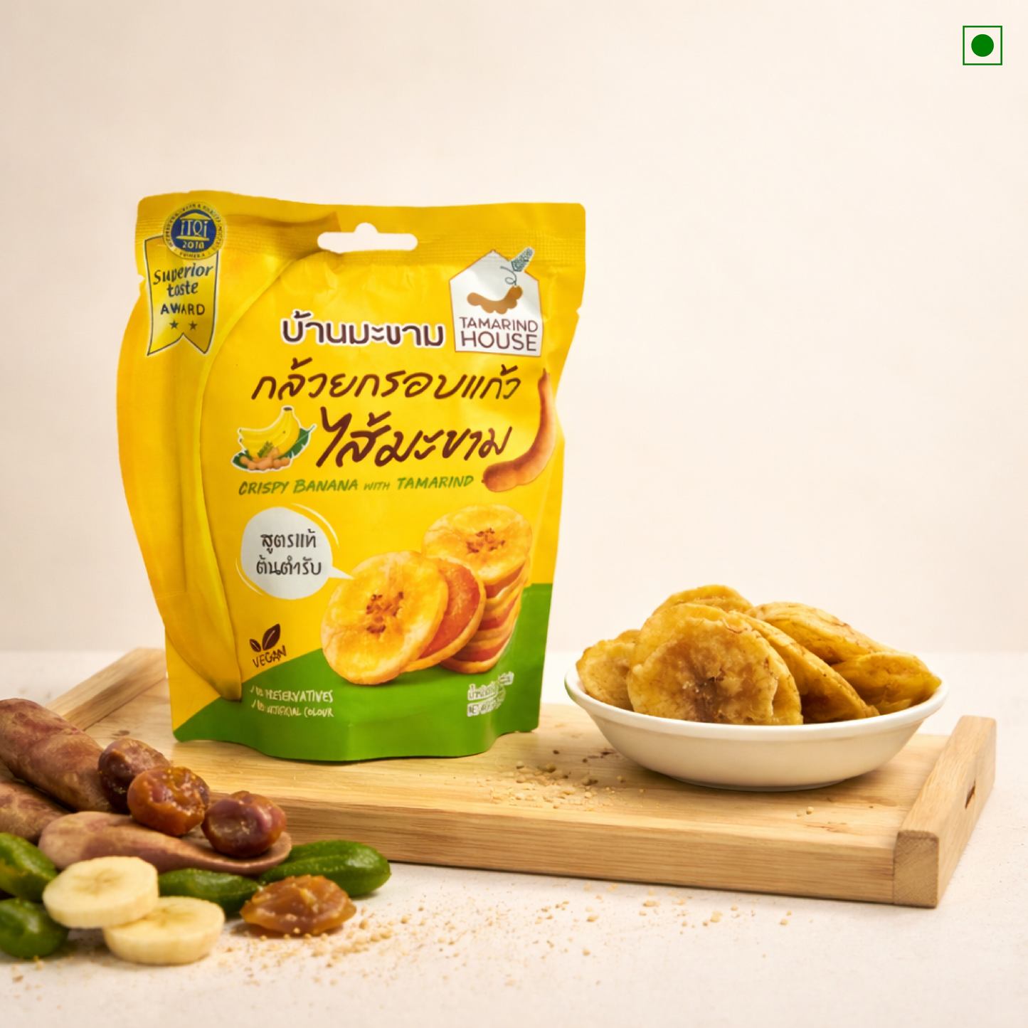 Yellow package of Tamarind House crispy banana snacks with dried fruits on a wooden board